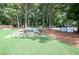 Expansive backyard featuring a stone patio with outdoor seating and a built-in grill, surrounded by mature trees at 1585 Elliott Rd, Mcdonough, GA 30252