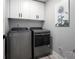 Modern laundry room with new washer and dryer, white cabinets, and decorative painting at 1585 Elliott Rd, Mcdonough, GA 30252
