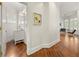 Hallway featuring hardwood floors, bright white walls, modern artwork, and an arched doorway leading to bathroom at 1079 Arbor Ne Trce, Atlanta, GA 30319
