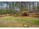 Expansive backyard featuring a mature trees, a wooden fence, and a retaining wall with plantings at 1303 Bass Dr, Woodstock, GA 30189
