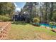 Spacious backyard with lush green lawn, mature trees, a blue swimming pool, and house in the background at 1303 Bass Dr, Woodstock, GA 30189