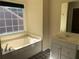 Bright bathroom features a soaking tub with a window and single sink vanity at 3259 S Pointe Ct, Atlanta, GA 30340