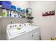 Efficient laundry room features a washer, dryer, and shelving for storage and organization at 4908 Waters Edge Trl, Roswell, GA 30075