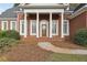Elegant home entrance featuring classic white columns, lush green bushes, and a brick walkway leading to the front door at 4385 Old Hamilton Mill Rd, Buford, GA 30518