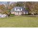 Picturesque brick home with elegant columns, lush greenery, and a sprawling lawn surrounded by colorful autumn trees at 4385 Old Hamilton Mill Rd, Buford, GA 30518