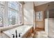Elegant bathroom featuring a soaking tub with tile surround and decorative stained-glass windows, capturing natural light at 2973 Heavenly Ln, Snellville, GA 30078