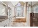 Luxurious bathroom showcasing a soaking tub below a beautiful stained-glass window, complemented by a glass-enclosed shower at 2973 Heavenly Ln, Snellville, GA 30078