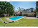 Backyard view featuring a swimming pool and well-kept yard, surrounded by mature trees at 2223 Jay Se Ln, Smyrna, GA 30080