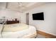 Well-lit bedroom with hardwood floors, ceiling fan, and large mounted TV at 5980 Eagle Tiff Ln, Sugar Hill, GA 30518