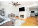 Open living room with fireplace, TV, hardwood floors, ceiling fan, and view into the kitchen at 5980 Eagle Tiff Ln, Sugar Hill, GA 30518