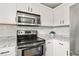 Up-close kitchen view with stainless steel appliances, white cabinets, granite countertops, and tile backsplash at 4248 Brighton Nw Way, Kennesaw, GA 30144
