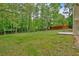 A spacious, green backyard is framed by tall trees and a partial view of the home's exterior, creating a private retreat at 8166 N Pine Cone Dr, Villa Rica, GA 30180