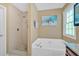 Bright bathroom with shower, large tub, and stylish beach art at 8166 N Pine Cone Dr, Villa Rica, GA 30180