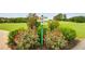 Landscaped community sign with direction to golf course tee boxes and the driving range surrounded by rose bushes at 8166 N Pine Cone Dr, Villa Rica, GA 30180