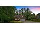 A single-Gathering home with a brick facade and two-car garage nestled among mature trees at 8166 N Pine Cone Dr, Villa Rica, GA 30180