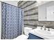 Bathroom with stylish wood-look accent wall, blue vanity, and shower with patterned curtain at 241 Rose Ridge Dr, Canton, GA 30115