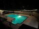 Outdoor pool at night is surrounded by string lights, stone accents, and a security fence at 241 Rose Ridge Dr, Canton, GA 30115