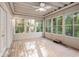 Bright sunroom featuring wood floors, a ceiling fan, and multiple windows offering a view of the surrounding trees at 241 Rose Ridge Dr, Canton, GA 30115