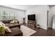 Cozy living room featuring wood floors, a comfortable sofa, and a large TV with decorative stand at 400 Paulownia Cir, Mcdonough, GA 30253