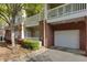Multi-story exterior showcasing brick accents, a private garage, and a balcony, all nestled in a landscaped setting at 8020 Woodland Ln, Alpharetta, GA 30009