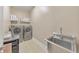 Laundry room showcases stainless steel washer and dryer with storage shelves and a utility sink at 1438 Kings Park Nw Dr, Kennesaw, GA 30152