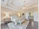 Elegant main bedroom featuring tray ceiling, chandelier, bench seating, and access to upstairs common area at 1438 Kings Park Nw Dr, Kennesaw, GA 30152