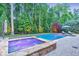 Backyard with a luxurious pool, hot tub with colored lights, and lush landscaping at 1438 Kings Park Nw Dr, Kennesaw, GA 30152