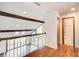 Upper hallway featuring hardwood floors, wood beams, and leads to a bathroom and a living room at 4983 Odins Way, Marietta, GA 30068