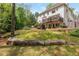 Large, grassy backyard with a stone retaining wall, mature trees, and a two-story home at 730 Denmead Se Ml, Marietta, GA 30067