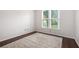 Minimalist bedroom with a neutral rug, hardwood floors, and a bright window at 12350 Edenwilde Dr, Roswell, GA 30075