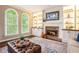 Inviting living room features a brick fireplace, custom built-ins, and bright windows with an oversized ottoman at 12350 Edenwilde Dr, Roswell, GA 30075