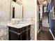 Stylish powder room with designer wallpaper, elegant mirror, and dark vanity at 12350 Edenwilde Dr, Roswell, GA 30075