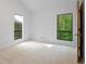Spare bedroom featuring two windows with wooded views and neutral carpeting at 2683 Fleur De Lis Pl, Atlanta, GA 30360