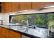 Kitchen featuring wood cabinets, black countertops, and a double sink under a window with garden views at 2683 Fleur De Lis Pl, Atlanta, GA 30360