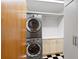 Laundry room featuring a stacked washer and dryer unit, white cabinetry, and black and white flooring at 2683 Fleur De Lis Pl, Atlanta, GA 30360