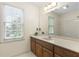Bright bathroom featuring a large mirror, double vanity, and a window for natural light at 8920 Willowbrae Ln, Roswell, GA 30076