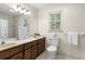 Light-filled bathroom featuring a double sink vanity, toilet, and bathtub shower combo at 8920 Willowbrae Ln, Roswell, GA 30076