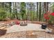 Stone patio with a fire pit, surrounded by trees and foliage and red Adirondack chairs at 8920 Willowbrae Ln, Roswell, GA 30076