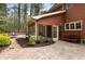 Exterior shot featuring a brick paver patio leading to screened in porch and wood fire pit area at 8920 Willowbrae Ln, Roswell, GA 30076