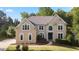 Beautiful two-story home surrounded by lush greenery with a manicured lawn and elegant architectural details at 915 Summer Wind Pl, Roswell, GA 30075