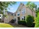 Elegant two-story tan home with a manicured lawn, decorative windows and lush landscaping at 915 Summer Wind Pl, Roswell, GA 30075