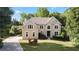 Beautiful tan two-story home with a lush green lawn, mature landscaping and a circular driveway at 915 Summer Wind Pl, Roswell, GA 30075