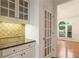 Kitchen counter area featuring granite countertops, glass front cabinets, and open doorway at 915 Summer Wind Pl, Roswell, GA 30075