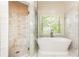 Bright bathroom featuring a glass enclosed shower and free standing tub, and large window at 3110 Dickson Ne St, Brookhaven, GA 30319