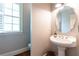 Elegant powder room features a pedestal sink, decorative mirror, and window with shutters at 3110 Dickson Ne St, Brookhaven, GA 30319