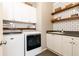 Efficient laundry room with white cabinets, wooden shelves, and modern washer/dryer units for convenience at 3110 Dickson Ne St, Brookhaven, GA 30319