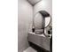 Modern gray bathroom with large round mirror over the vanity and a vessel sink with a black faucet at 8610 Sentinae Chase Dr, Roswell, GA 30076