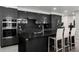Modern black kitchen featuring sleek cabinets, stainless steel appliances, and a center island with barstool seating at 8610 Sentinae Chase Dr, Roswell, GA 30076