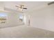 Spacious main bedroom featuring tray ceiling, ceiling fan, carpeted floor, and abundant natural light at 13562 Whitman Ln, Covington, GA 30014