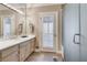 Bathroom with white vanity, marble countertop, and tiled floors leads to a glass shower and shuttered door at 24 Ball Creek Hl, Atlanta, GA 30350